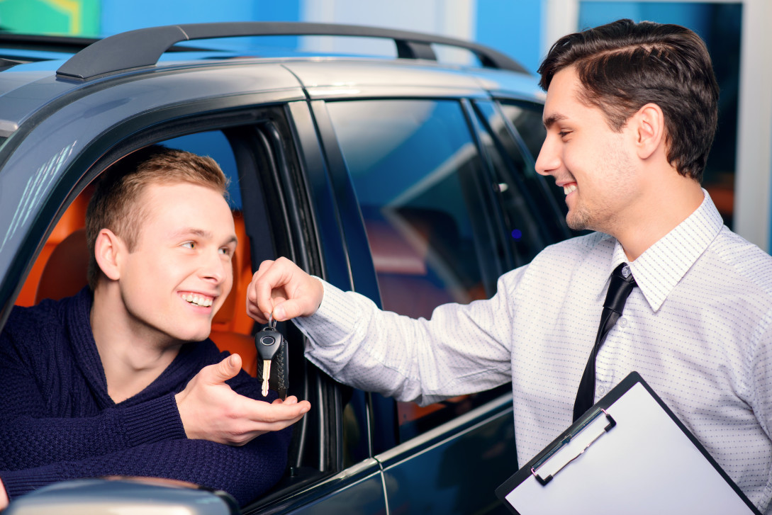 Sales manager giving key from the new car